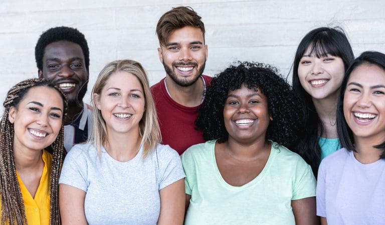Happy friends from different races and culture laughing in front of phone camera - Young millennial people having fun together - Multiracial generation concept - Main focus on center girls