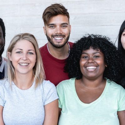 Happy friends from different races and culture laughing in front of phone camera - Young millennial people having fun together - Multiracial generation concept - Main focus on center girls