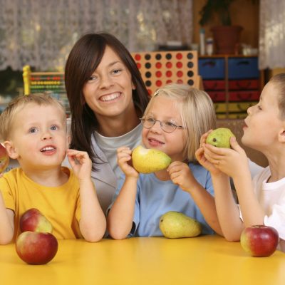 teacher and three preschoolers having break for fruit