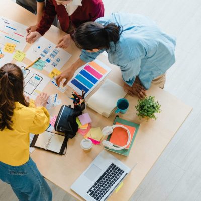 Multiracial group of young creative people in smart casual wear discussing business brainstorming meeting ideas mobile application software design project in modern office. Coworker teamwork concept.